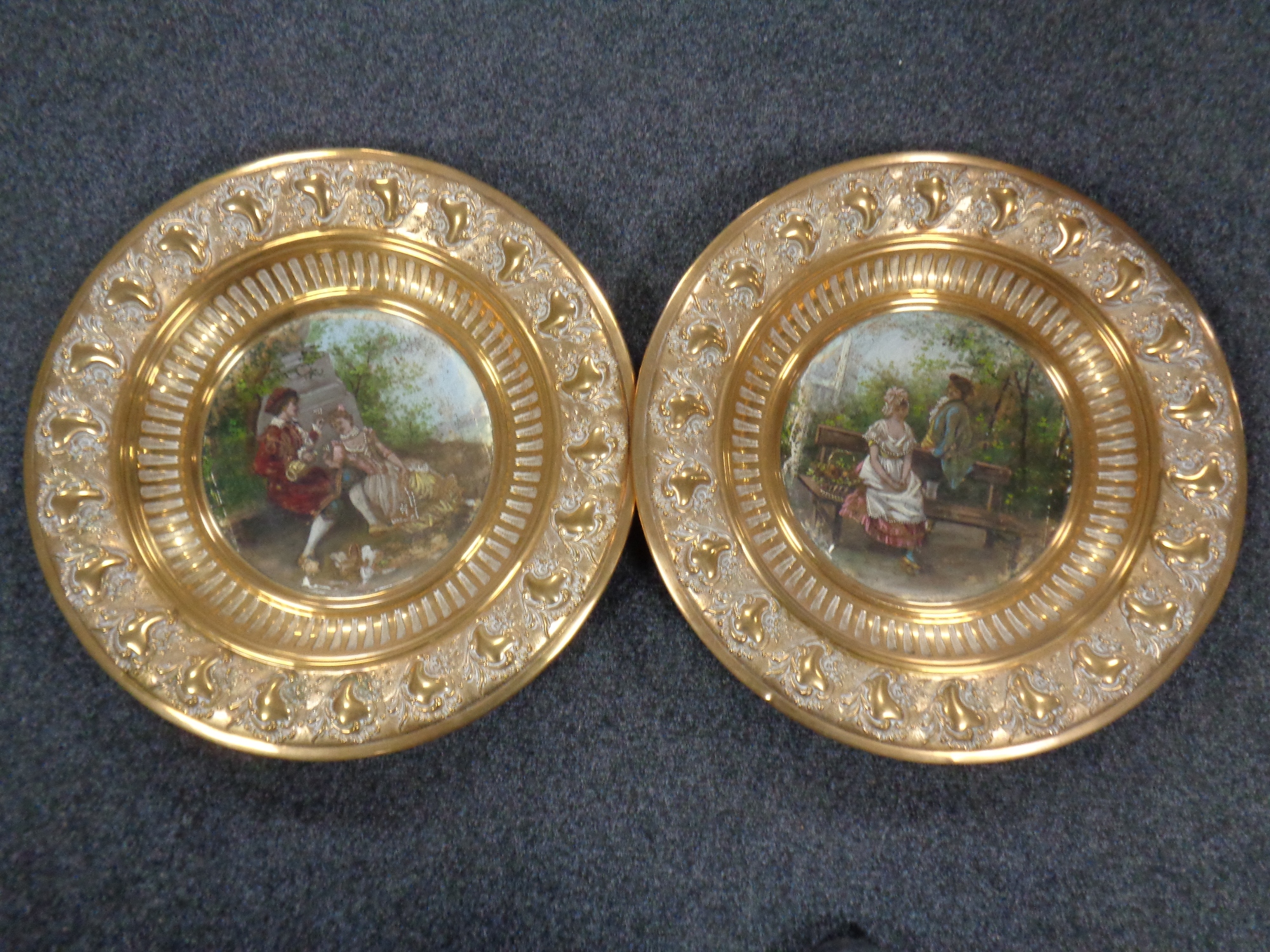 A pair of hand painted brass embossed wall plaques