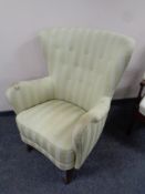 A mid 20th century wing back armchair in striped button fabric