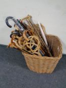 A large wicker log basket containing a large quantity of assorted walking sticks, walking canes,