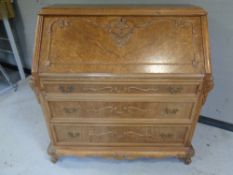 An antique oak writing bureau with carved moulding fitted with three drawers