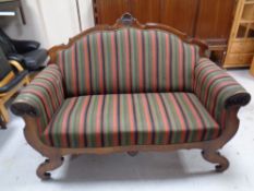An antique mahogany framed hall settee upholstered in a multi coloured striped fabric