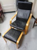 A wood framed black leather relaxer armchair with matching footstool