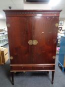 A mahogany double door cabinet on raised legs