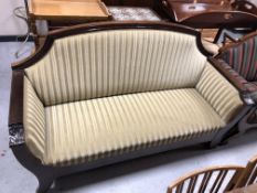 An antique mahogany framed hall settee upholstered in a gold striped fabric