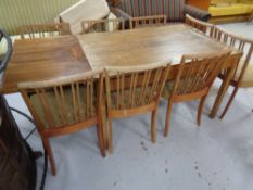 A mid 20th century pull out dining table together with a set of eight rail back chairs