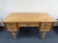 An antique stripped pine five drawer writing desk on raised legs