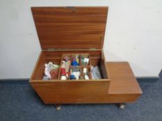 A mid 20th century teak sewing box on castors containing sewing threads and accessories