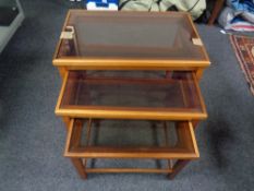 A nest of three 20th century teak smoked glass topped tables