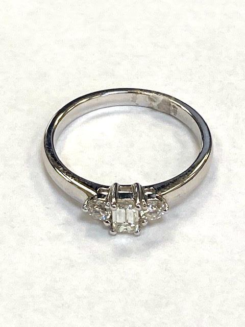 An 18ct white gold three stone diamond ring, set with a central emerald cut stone, size M/N.