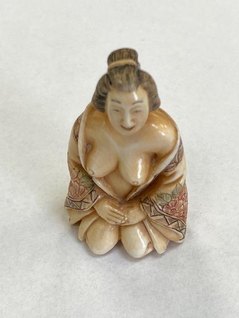 A carved Japanese netsuke nude wearing a gown, height 45 mm.