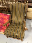 An oak framed wingback armchair upholstered in a striped fabric