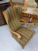 An oak framed wingback armchair upholstered in a striped fabric