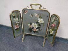 A brass Art Nouveau three-way folding fire screen with hand painted floral decoration