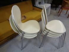 A set of eight white stacking chairs on metal legs