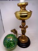 An antique brass oil lamps on figural column and later glass mosaic shade (converted)