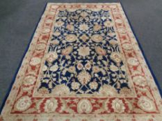 A floral woolen carpet on blue ground 199 cm x 302 cm.