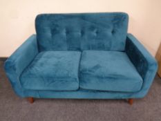 A contemporary two seater settee in teal fabric