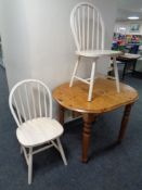 An oval pine extending dining table with leaf and two kitchen chairs