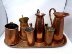 An antique oval copper tray together with six further antique copper jugs,