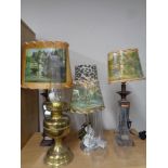 A brass oil lamp with three glass chimneys together with four contemporary table lamps,