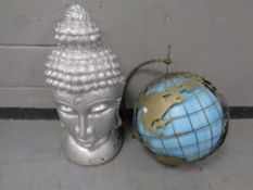 A painted concrete Buddha head together with a metal globe