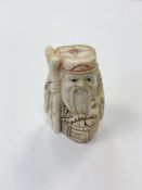 A small Japanese bone carving - Village elder with a basket by his feet.