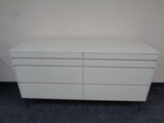 A contemporary six drawer chest in cream finish on raised metal legs