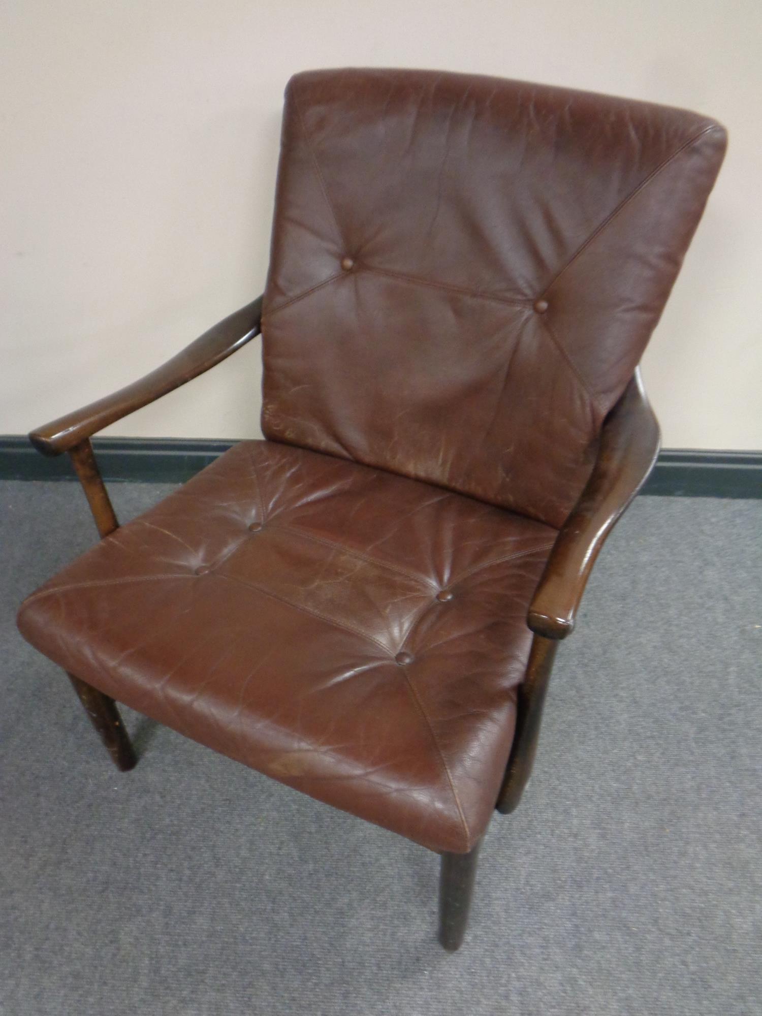 A Scandinavian stained beech framed armchair in brown buttoned leather