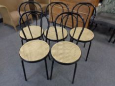 A set of five black tubular metal bergere seated dining chairs