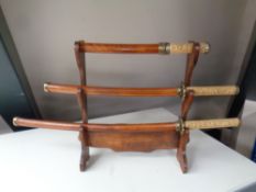 A reproduction graduated set of three Samurai swords on stand