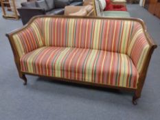 An early 20th century mahogany framed settee in cabriole legs in striped fabric