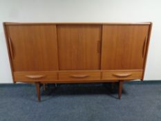 A mid century Danish triple sliding door sideboard fitted with three drawers on raised legs