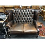 A Chesterfield brown buttoned leather two seater wing backed settee