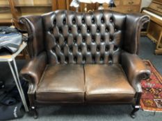 A Chesterfield brown buttoned leather two seater wing backed settee