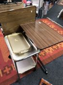 Two wood effect bed tables together with a gilt two tier trolley and two further tea trays