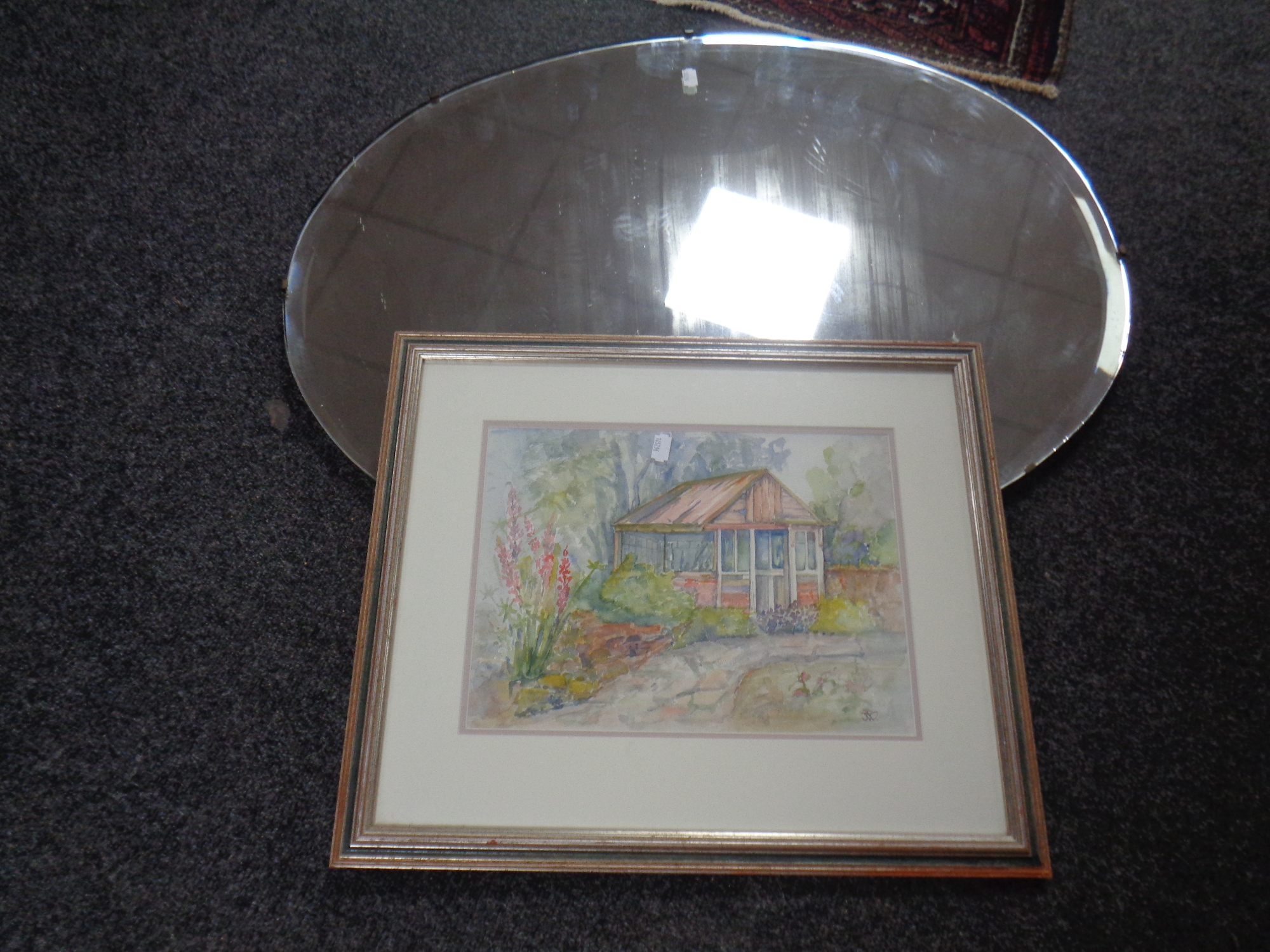 A 20th century oval frameless bevelled mirror together with a watercolour - Garden scene initialled
