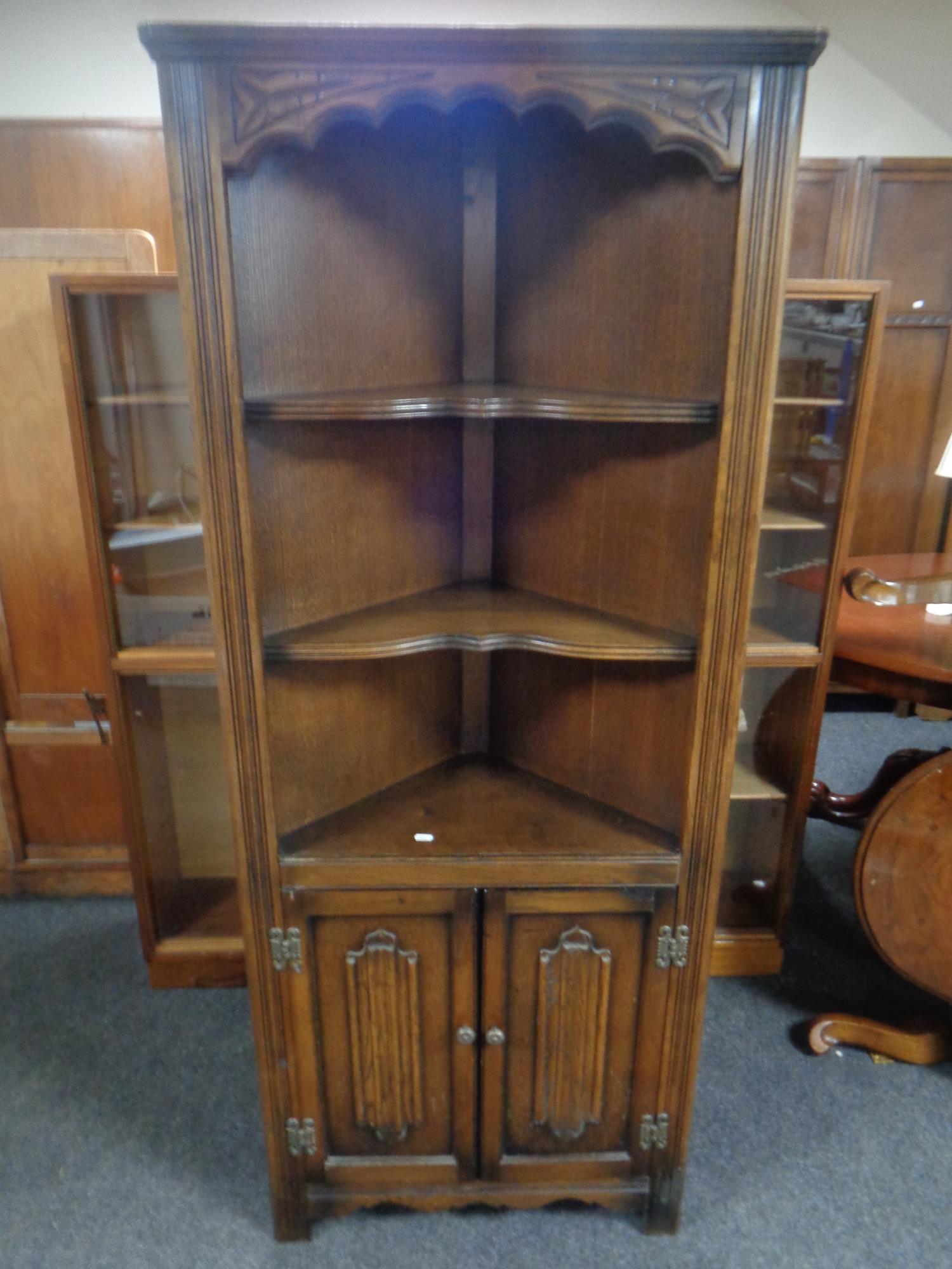 A carved oak linen fold open corner display cabinet