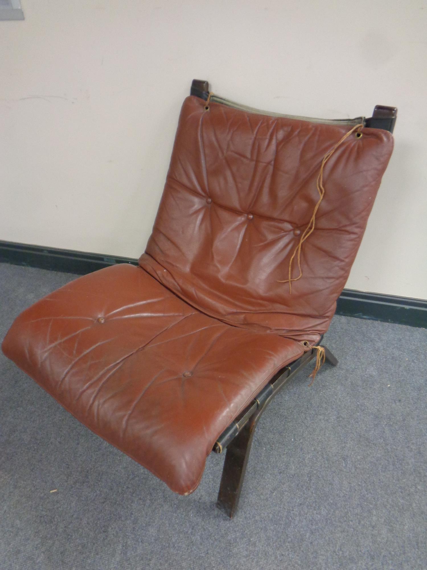 A 20th century Danish low backed lounger chair with brown buttoned leather cushion