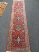 A Caucasian runner of geometric design on red ground, signed,