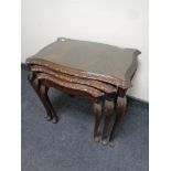 A nest of three mahogany serpentine fronted tables with plate glass tops