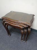 A nest of three mahogany serpentine fronted tables with plate glass tops