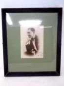 A framed monochrome photograph of George Formby bearing facsimile autograph