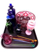 A tray of two blue glass apothecary bottles, cranberry glass fruit bowl,