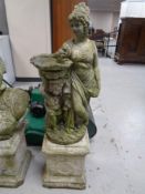 A concrete garden figure of a lady and cherub on plinth.