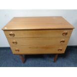 A mid 20th century teak three drawer chest on raised legs