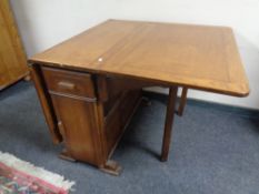 A mid 20th century oak drop leaf storage dining table