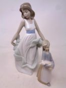 Lladro figure of a girl holding a piglet together with a Nao figure of a girl in dress