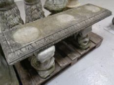 A concrete garden bench with Koi fish supports.