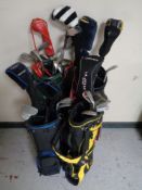 Four golf bags containing an assortment of golf clubs including Slazenger, Taylor made,