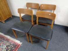 A set of four mid 20th century teak dining chairs with black vinyl seats